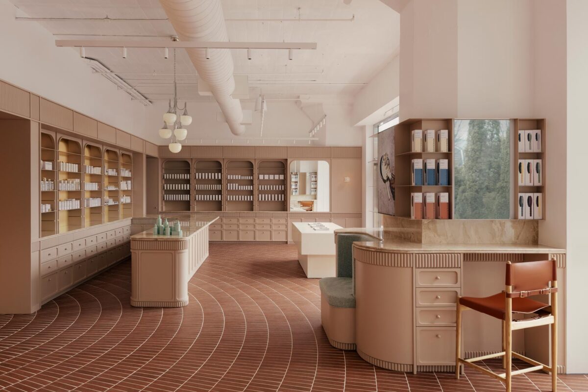 Interior view of the Living Beauty concept store in Toronto, featuring a curved central counter, arched niches inspired by historic pharmacies, and terracotta-colored porcelain tile flooring with a concentric pattern.