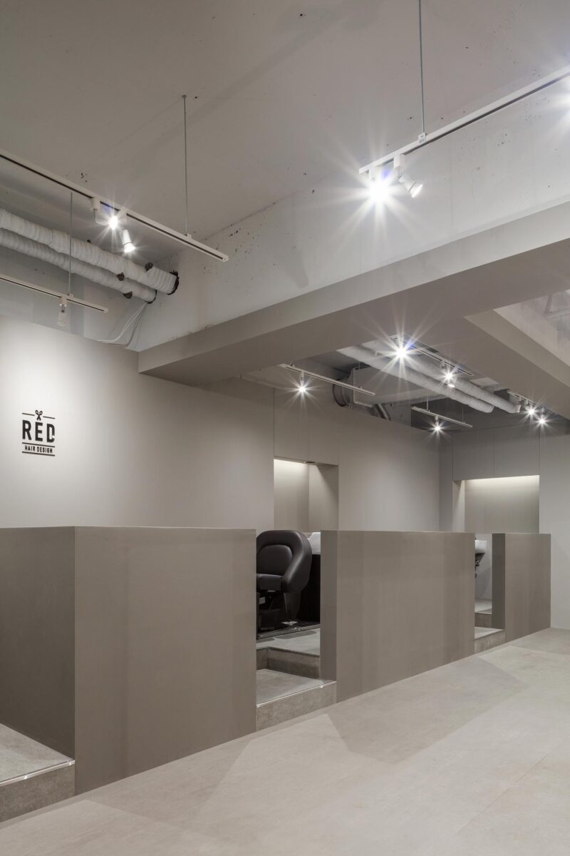 Wash area at RED Hair Design in Tokyo featuring raised volumes, ergonomic chairs and technical ceiling lighting in an essential interior