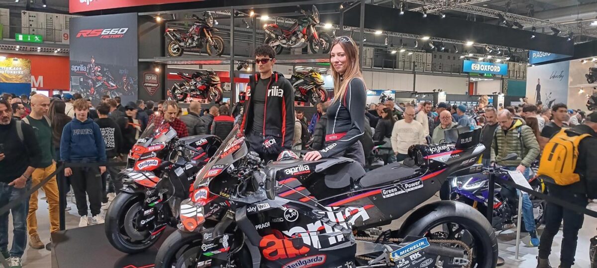 Stand Aprilia a EICMA con moto RS 660 Factory esposte su pedana, pubblico numeroso e allestimento con struttura multilivello.