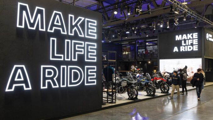 Stand BMW Motorrad a EICMA con maxi LED wall “Make Life a Ride” e area espositiva con moto adventure e urban.