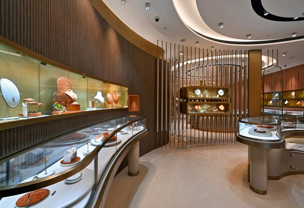 Contemporary jewellery store interior with curved glass display counters, fluted wood walls and vertical brass partitions, Eish Jewels Indore