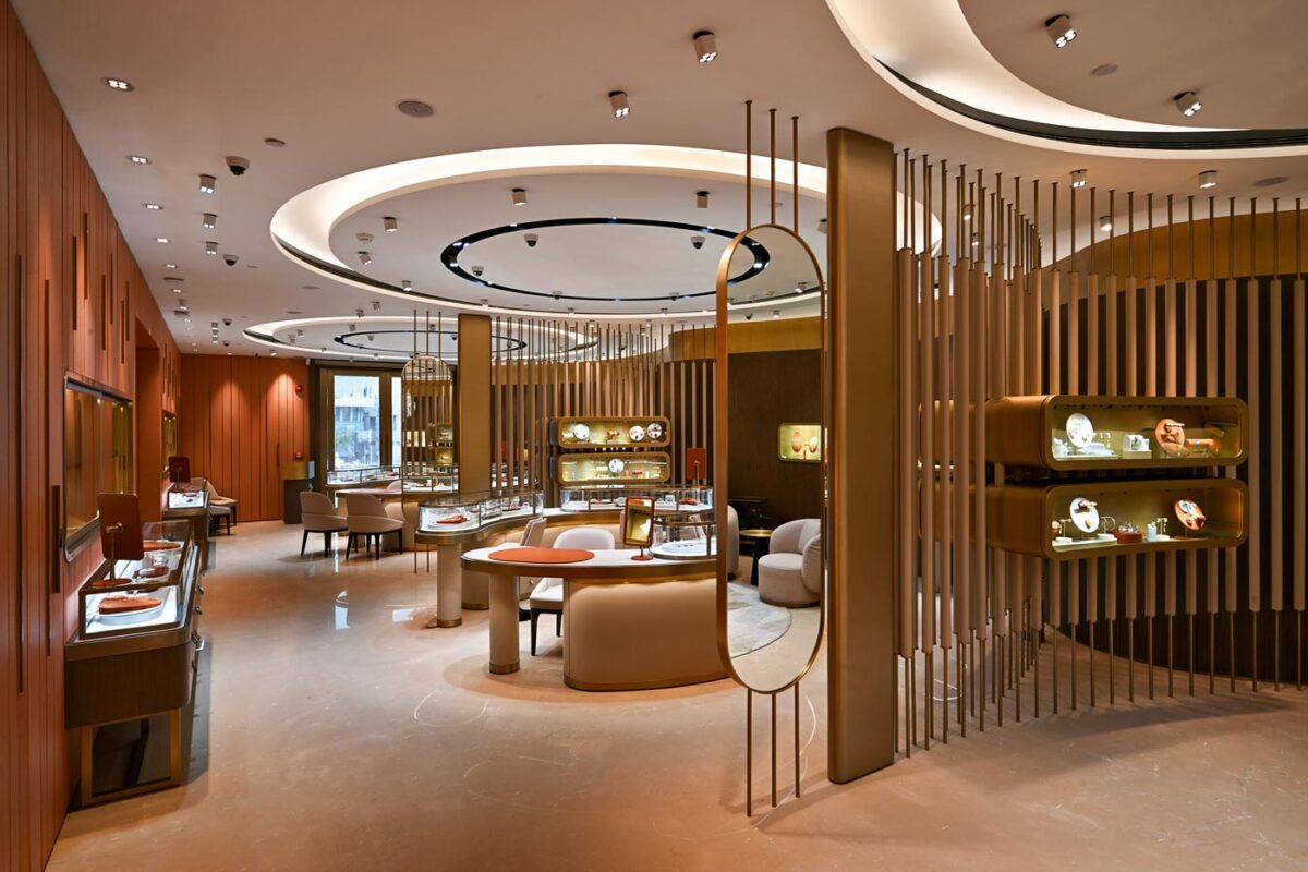Contemporary jewellery store with fluid layout, curved glass display counters, vertical brass partitions and concentric ceiling light rings, Eish Jewels Indore