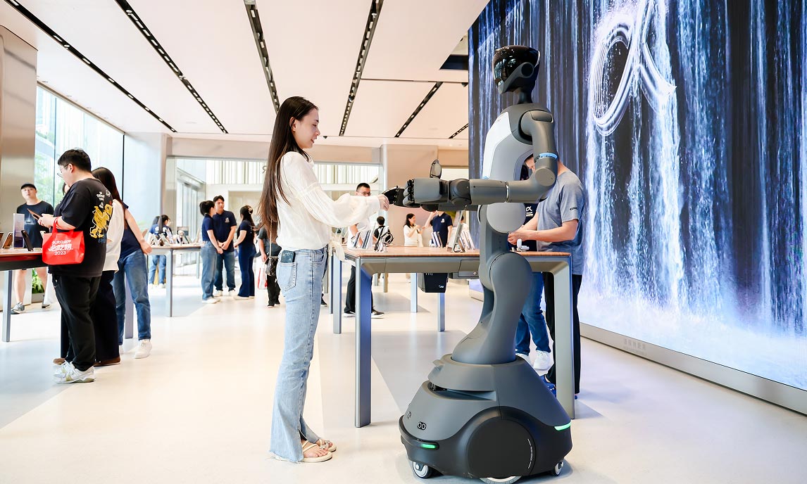 Interazione tra visitatrice e robot mobile nell’area espositiva dell’HONOR Flagship Store Shenzhen Bay, con schermo immersivo sullo sfondo