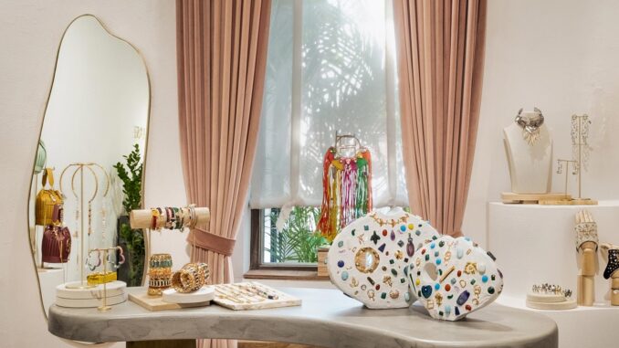 Interno della Gioielleria Outhouse a Goa progettata da Studio Hasta, tavolo espositivo in pietra con gioielli, elementi scultorei e tende rosa salmone