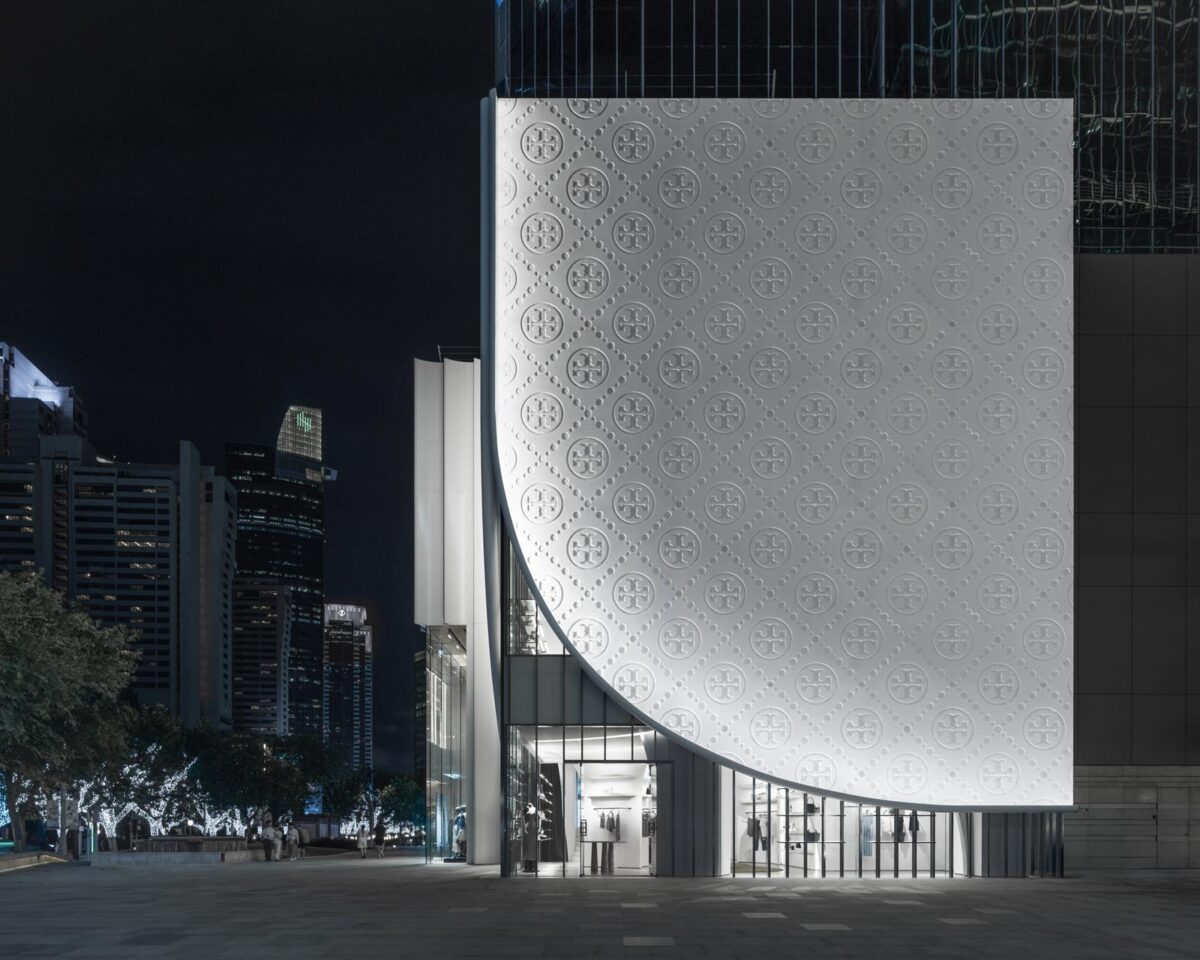 Curved faรงade of the Tory Burch flagship in Shanghai with illuminated white textured cladding at night