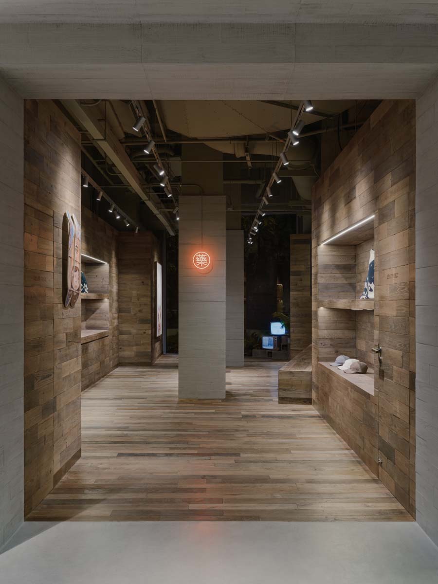 Inner corridor clad in reclaimed wood with illuminated display niches and a light sign at the back