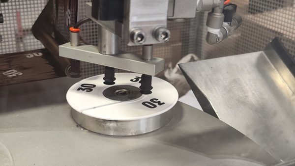 Industrial machine printing and marking plastic size tags used for visual merchandising in retail displays.