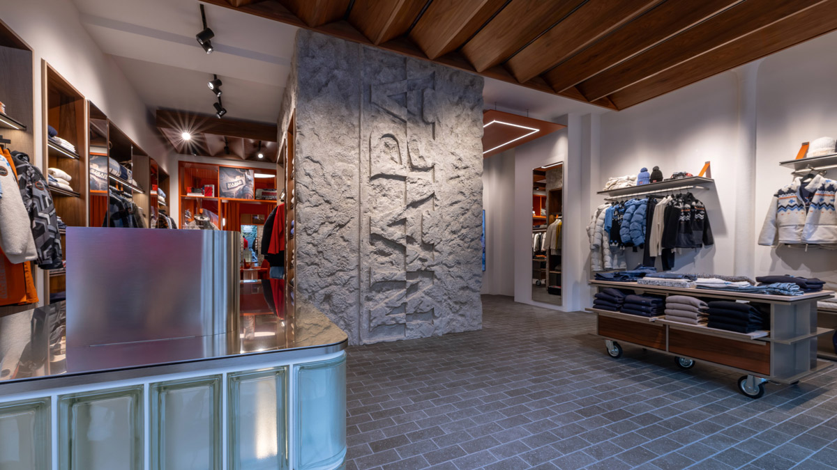 Napapijri store interior with central textured wall, wood and metal furnishings and apparel display