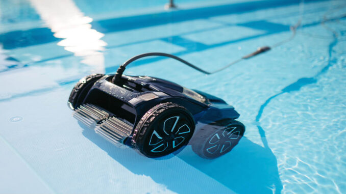 Robot pulitore automatico per piscina, di colore nero, immerso nell’acqua limpida mentre pulisce il fondo, con cavo visibile e riflessi di luce sulla superficie.