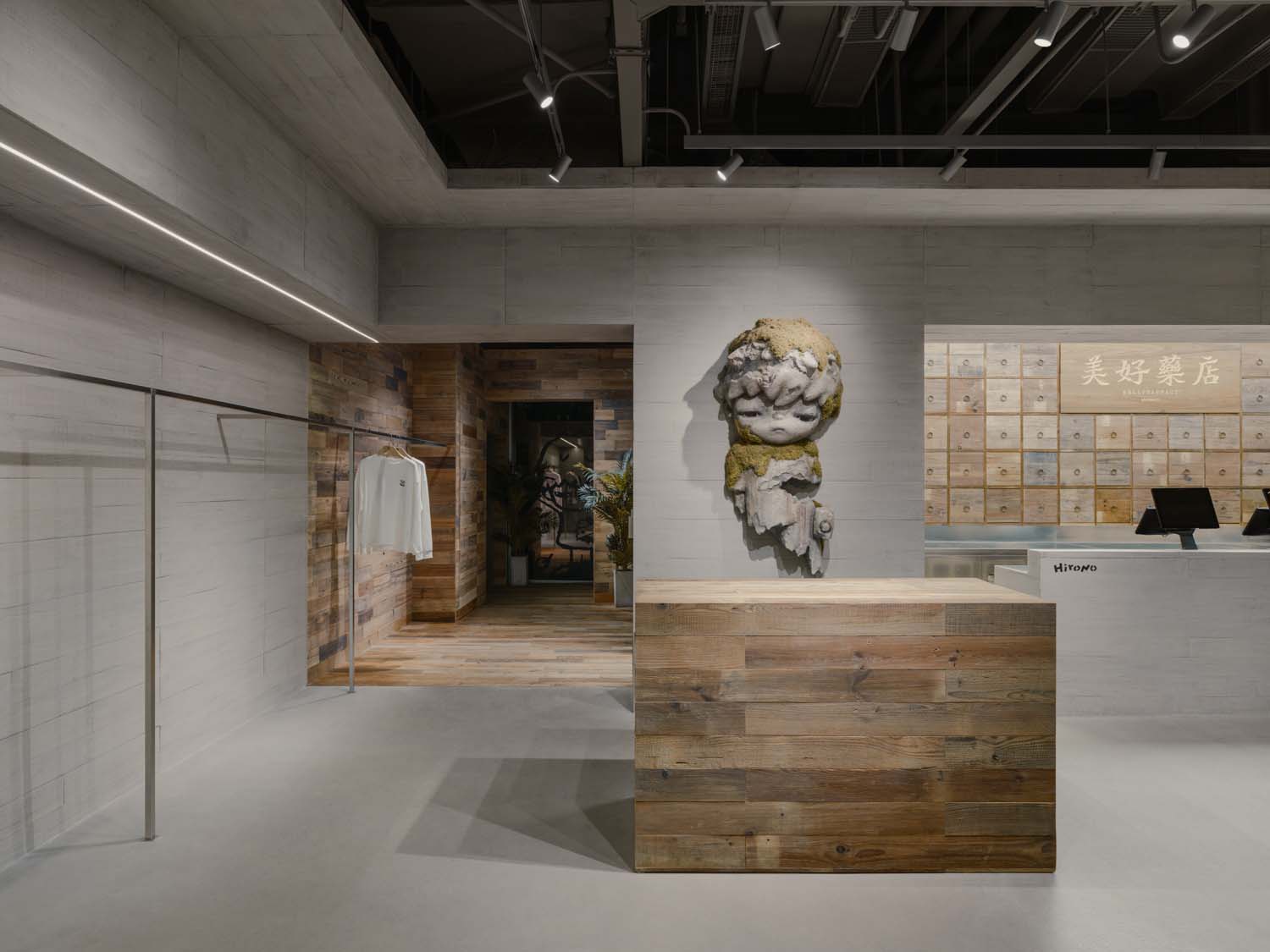 Totemic Hirono sculpture in the retail space between light concrete surfaces and a wooden display counter