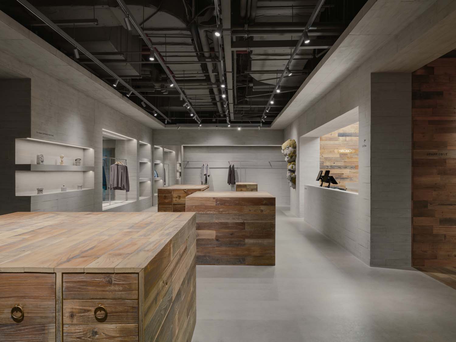 Interior view of the Hirono store in Shanghai with reclaimed wood display islands, concrete walls and checkout counter at the back