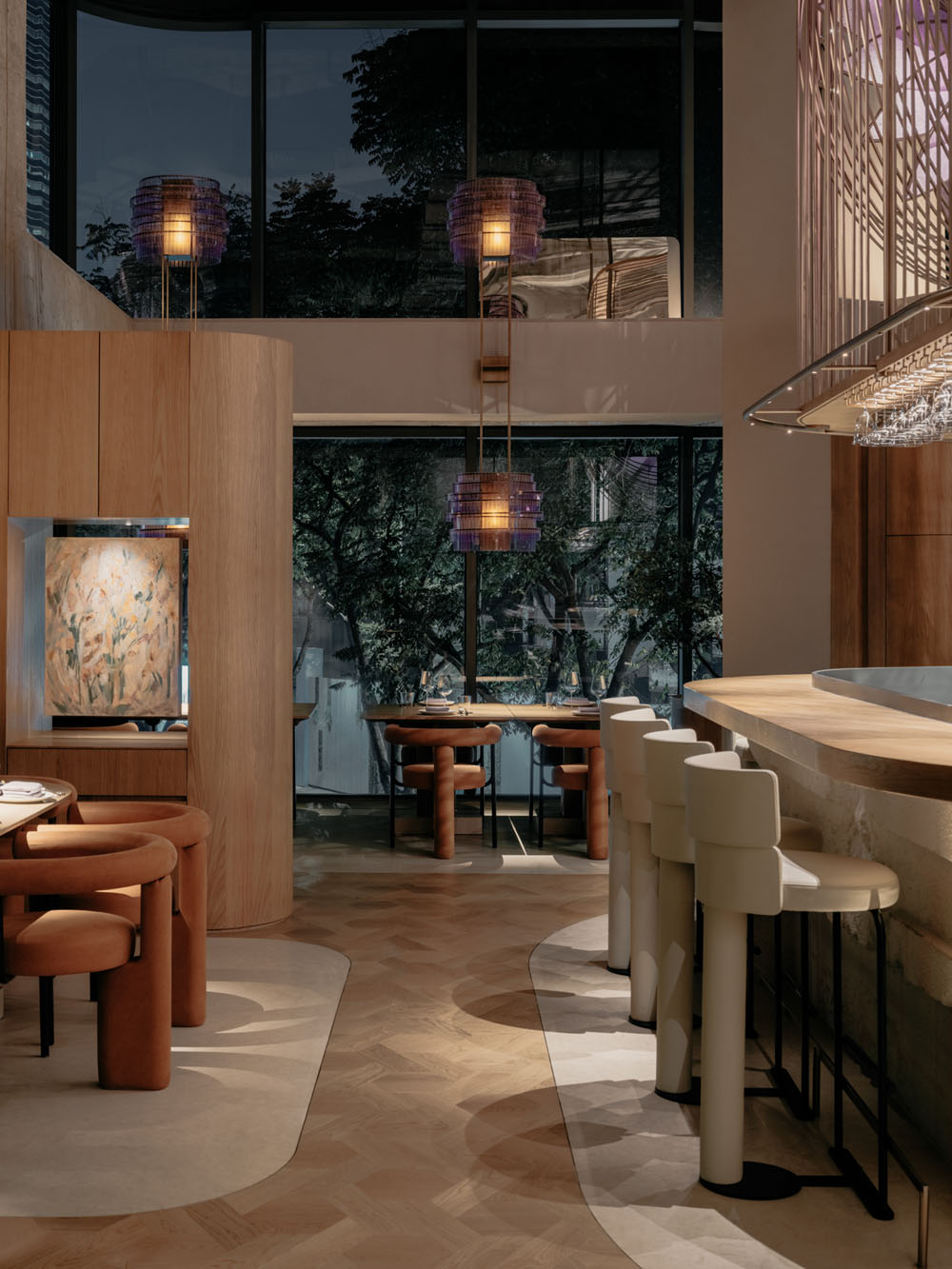 Central counter at Aster restaurant with suspended metal structure and purple lighting installation