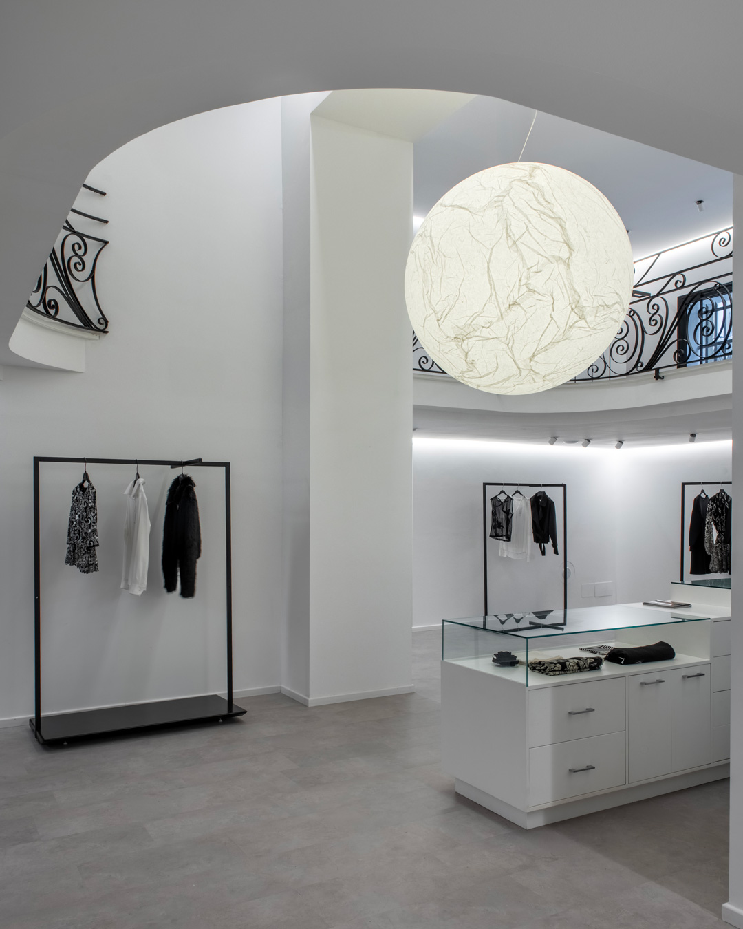 White spiral staircase with decorative iron railings and mannequins in the central space of the store