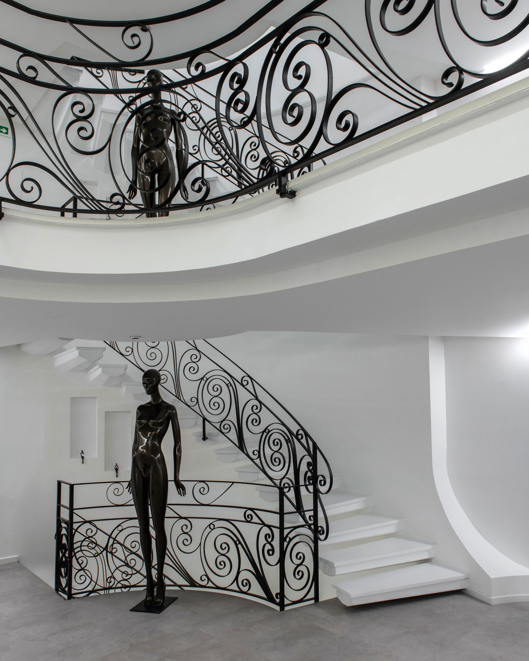 Detail of the spiral staircase and balcony with iron railing and minimal white surfaces