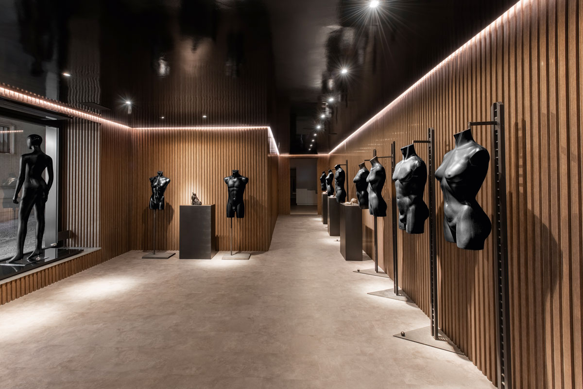 Entrance with slatted wood wall cladding, linear LED lighting and mannequins along the display path in the concept store