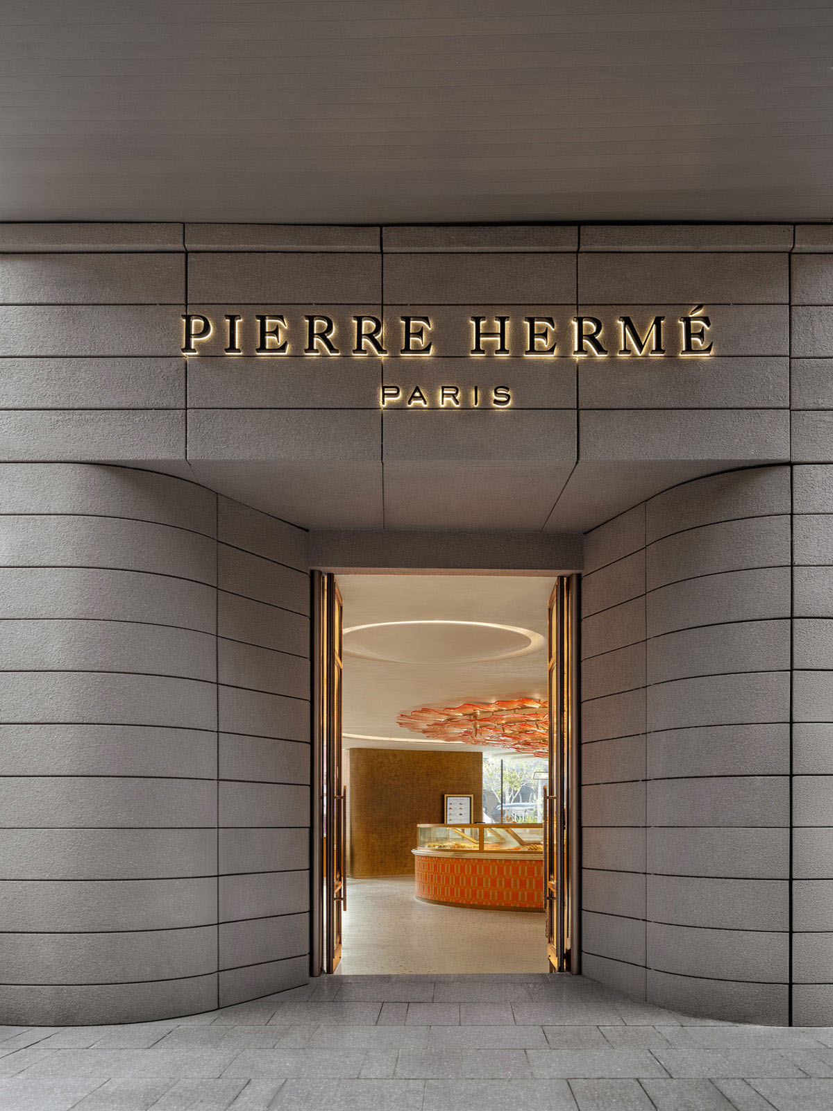 Ingresso del flagship store Pierre Hermé Singapore con vetrate e volumi curvi