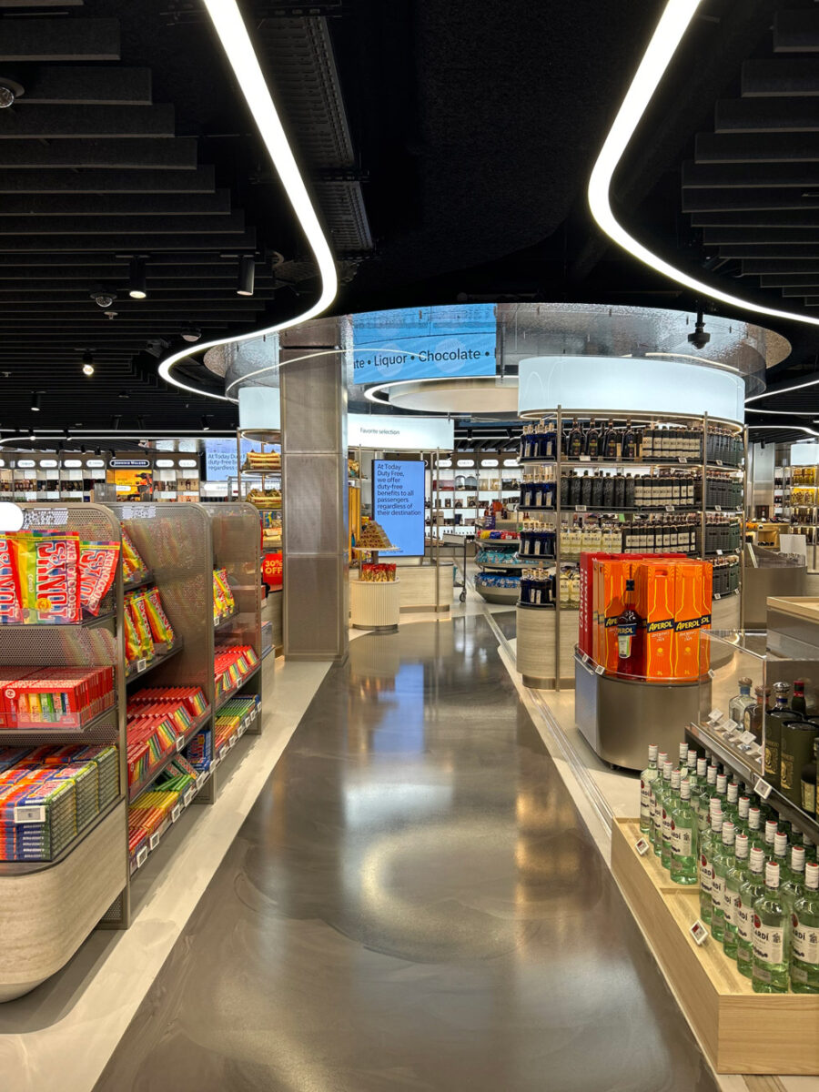 Retail design duty free aeroporto Schiphol con layout immersivo, illuminazione lineare e arredi modulari per food e liquor