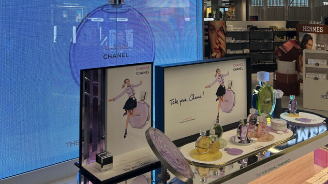 Area beauty con visual merchandising cosmetico e display digitale nel duty free Schiphol con brand di lusso
