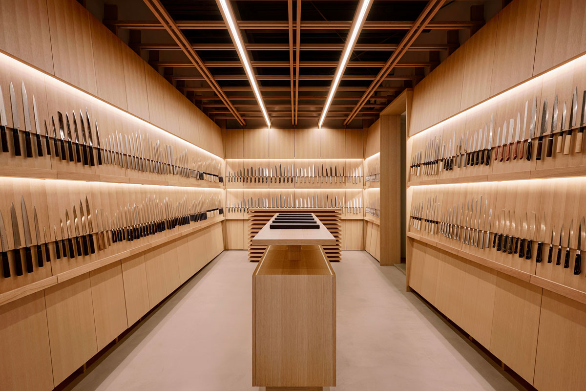 Interno di Tojiro Knife Gallery Osaka con pareti in legno, display di coltelli e illuminazione lineare a soffitto
