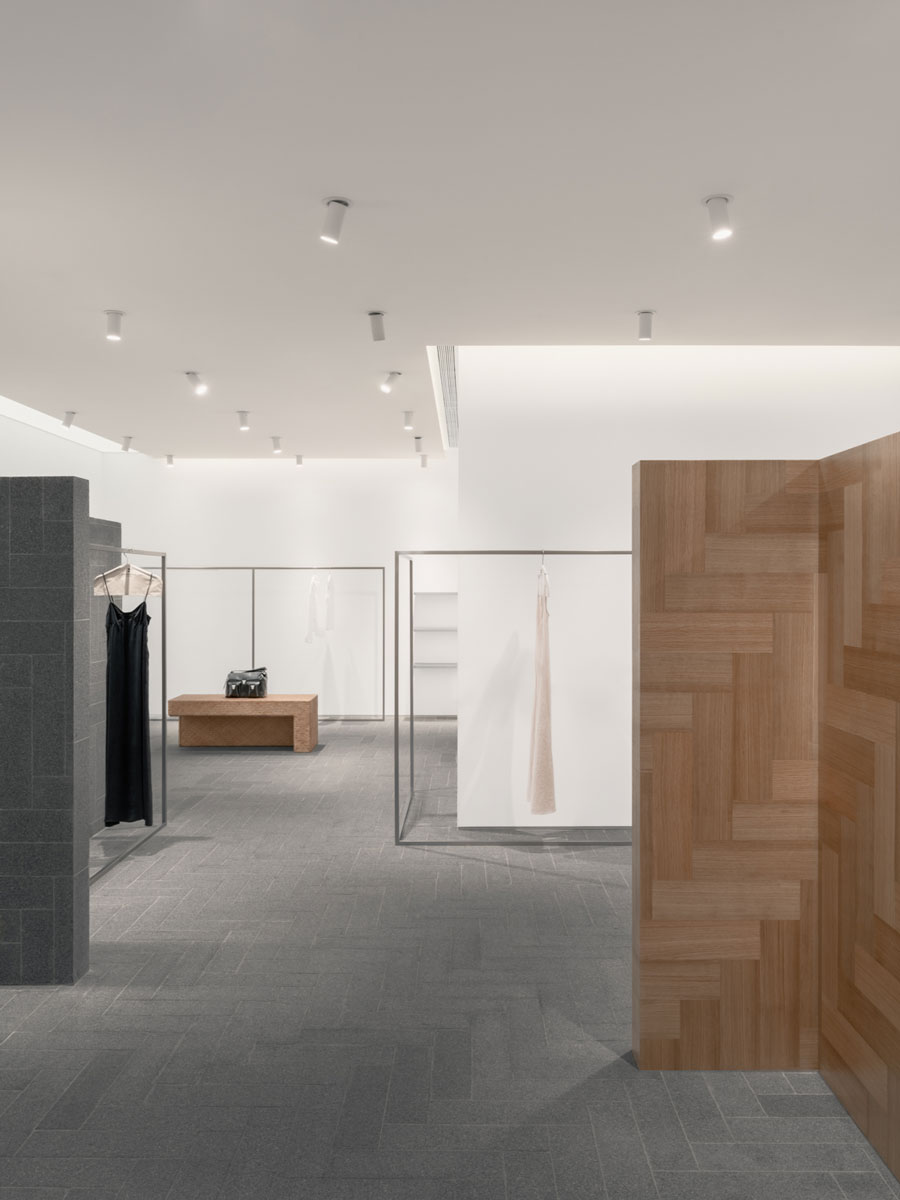 Interior of the A SURNAME fashion store in Shenzhen with granite surfaces, geometric wooden walls and minimalist display layout