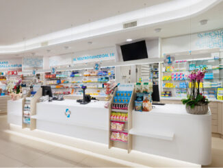 Area dermocosmesi in farmacia con espositori retroilluminati, banco consulenza e pavimento chiaro