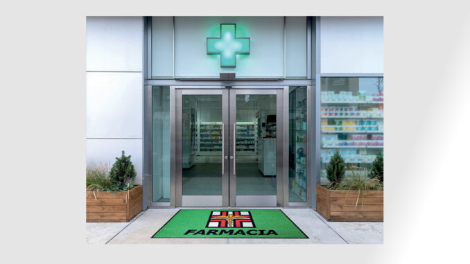 Ingresso di farmacia con zerbino tecnico personalizzato coordinato con l’identità visiva del punto vendita