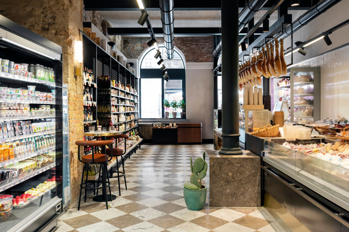 Banco gastronomia del Retrobottega Prezzemolo & Vitale con salumi sospesi, pavimento in marmo a dama e colonne in ghisa nel centro storico di Palermo