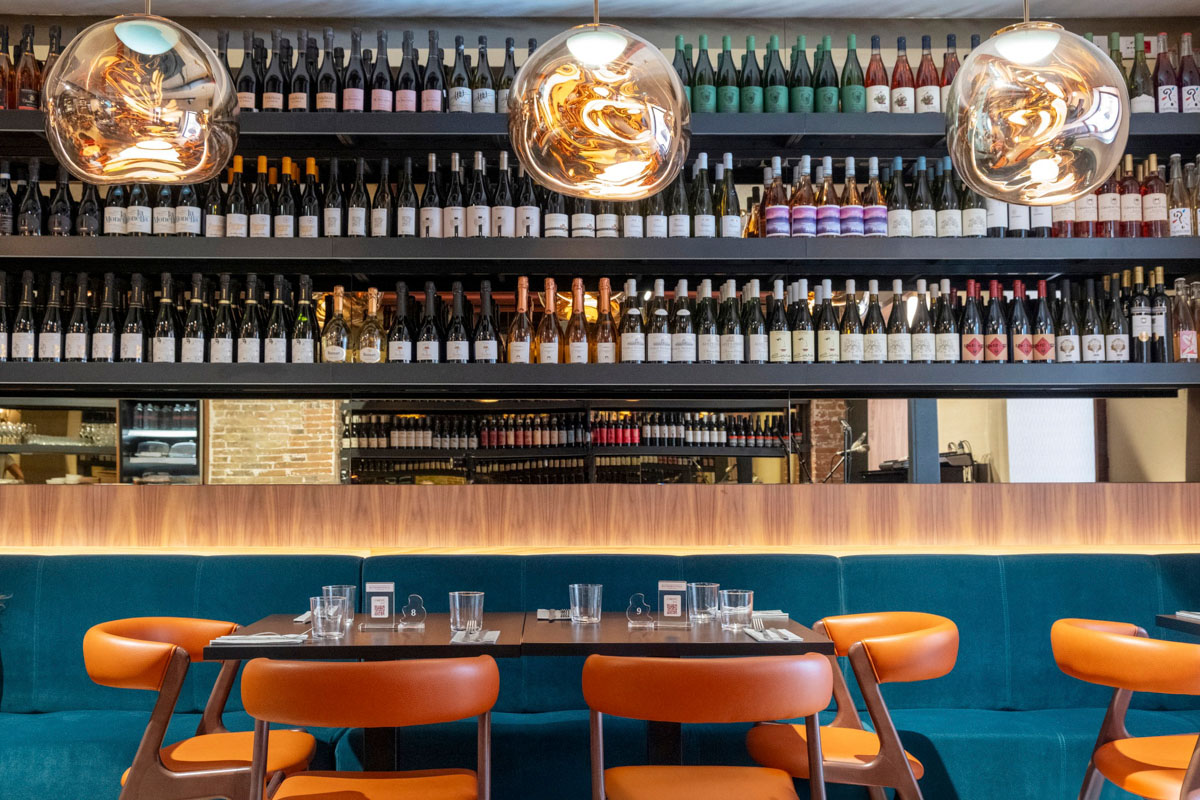Dettaglio delle bottigliere retroilluminate e delle sedute della sala consumazione del wine bar
