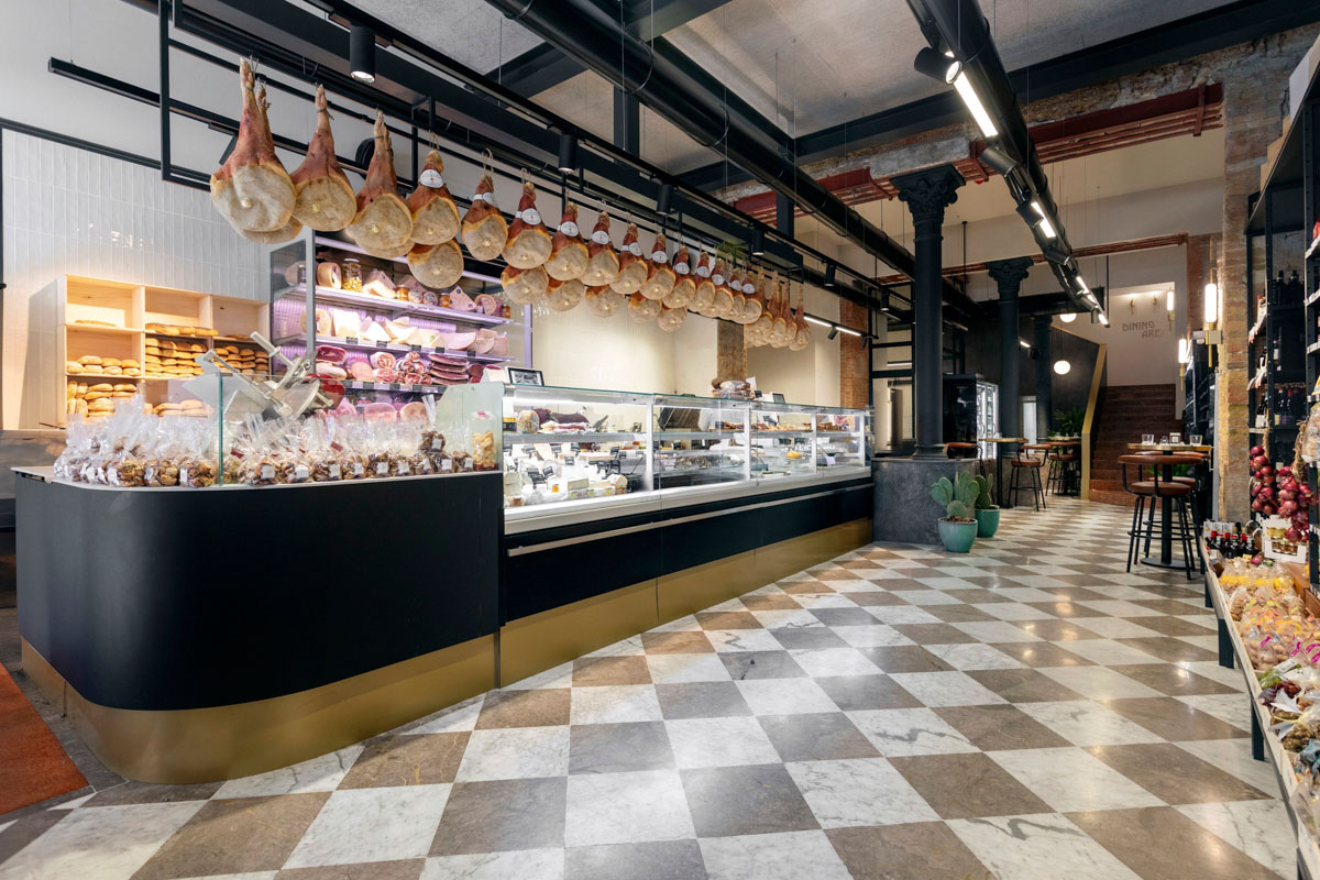 Banco gastronomia del Retrobottega Prezzemolo & Vitale con salumi sospesi, pavimento in marmo a dama e colonne in ghisa nel centro storico di Palermo
