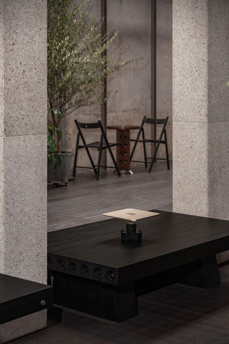 Black wooden lounge seating integrated between textured columns and material surfaces inside TOMOSOON Cafe