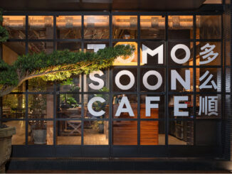 Facciata vetrata di TOMOSOON Cafe a Shenzhen con struttura metallica nera, illuminazione calda e bonsai orientale davanti all’ingresso