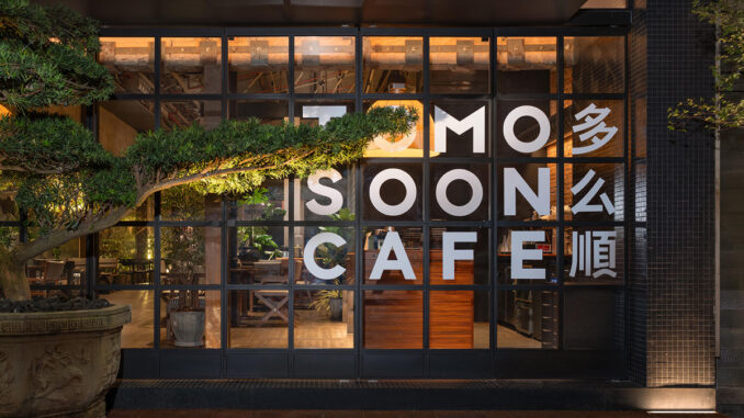 Facciata vetrata di TOMOSOON Cafe a Shenzhen con struttura metallica nera, illuminazione calda e bonsai orientale davanti all’ingresso