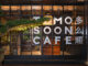 Facciata vetrata di TOMOSOON Cafe a Shenzhen con struttura metallica nera, illuminazione calda e bonsai orientale davanti all’ingresso
