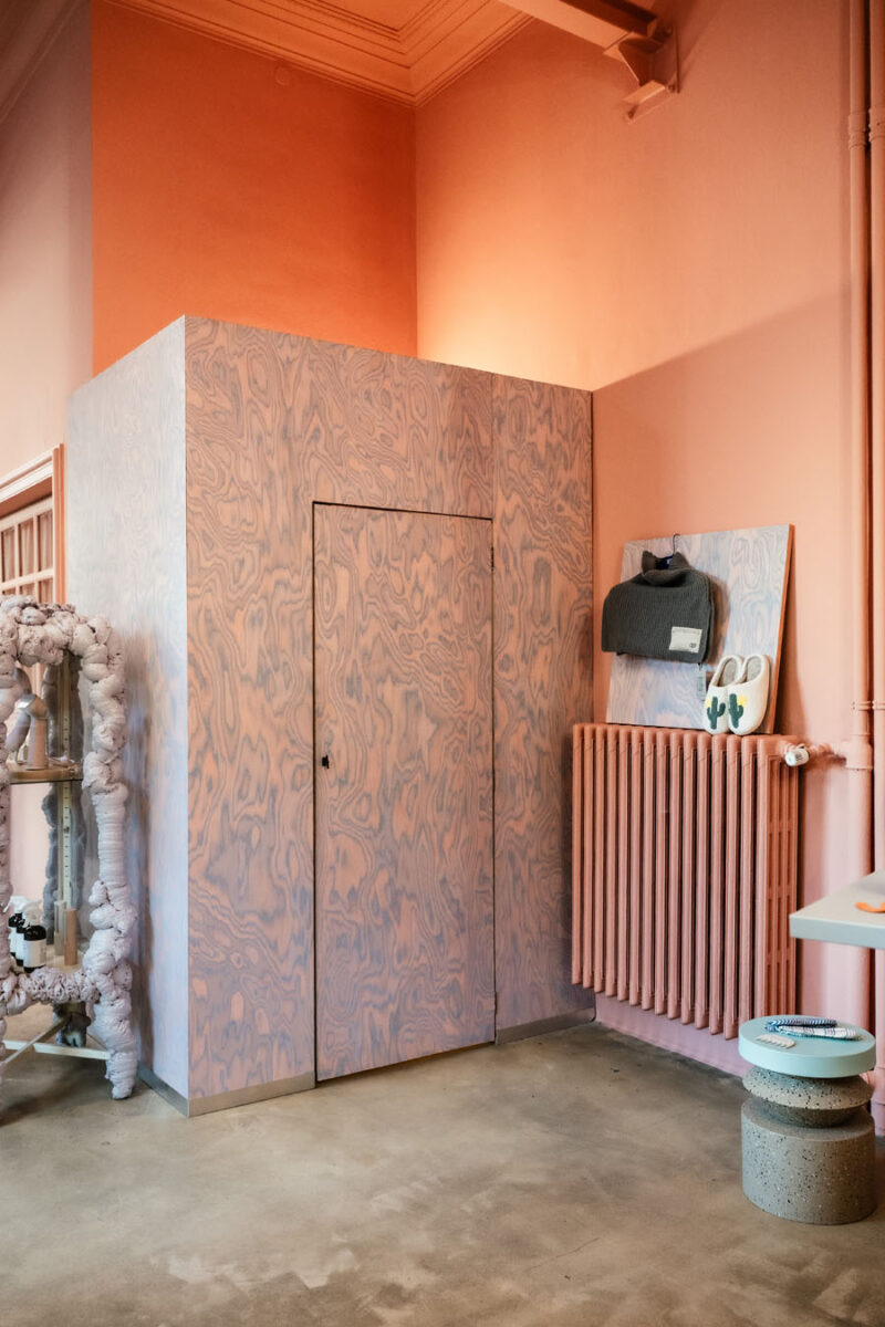 Integrated fitting room with decorative panel cladding and pink walls inside 16. Concept Store in Turin.
