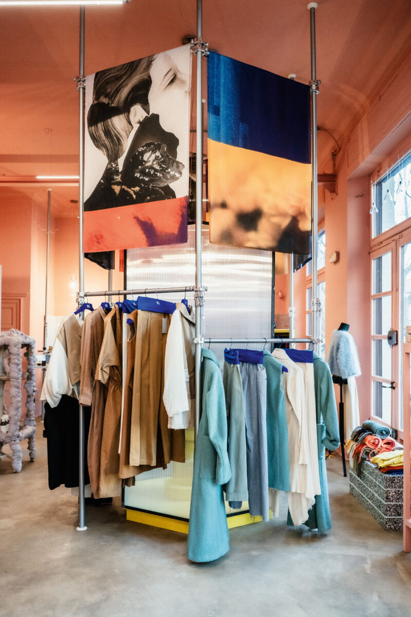 Modular display system with metal structures, garments and artistic banners at the centre of 16. Concept Store in Turin.