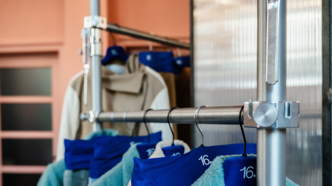 Dettaglio del sistema espositivo modulare con struttura metallica e capi di abbigliamento in 16. Concept Store a Torino.
