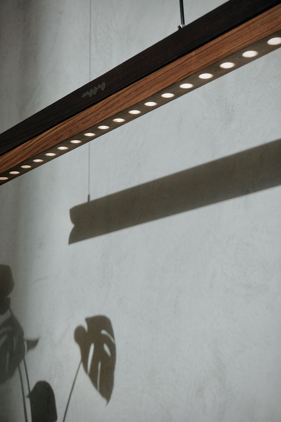 Moono pendant lamp suspended above a table with adjustable linear lighting
