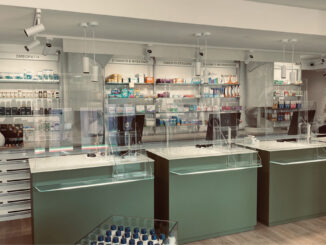 Vista laterale del banco farmacia con protezioni trasparenti e pareti espositive