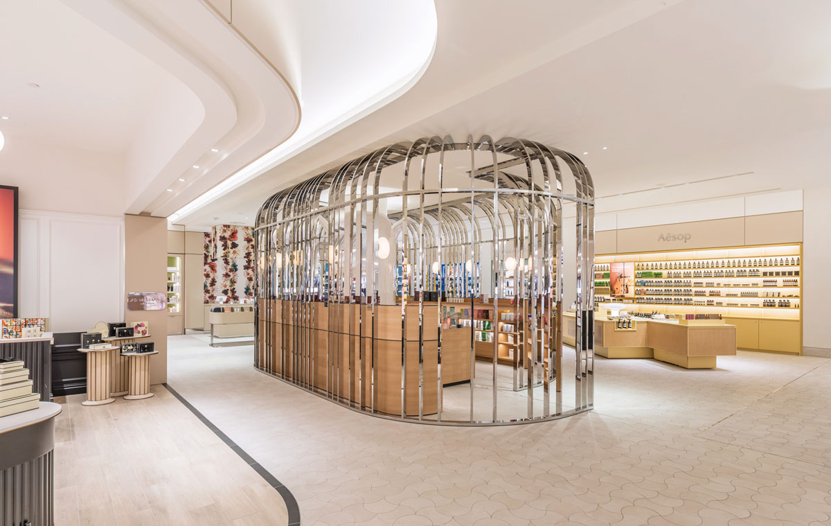 Central display pavilion at Rennaï Beauty Hall featuring a curved metal structure, custom furnishings and an integrated fragrance area