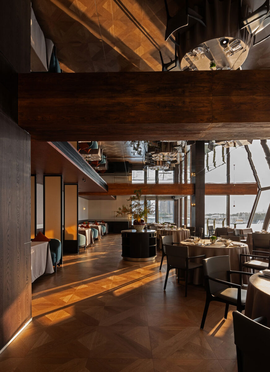 Dining room at Shu Pavilion Restaurant in Shanghai featuring wooden flooring, mirrored ceiling and panoramic windows overlooking the Huangpu River