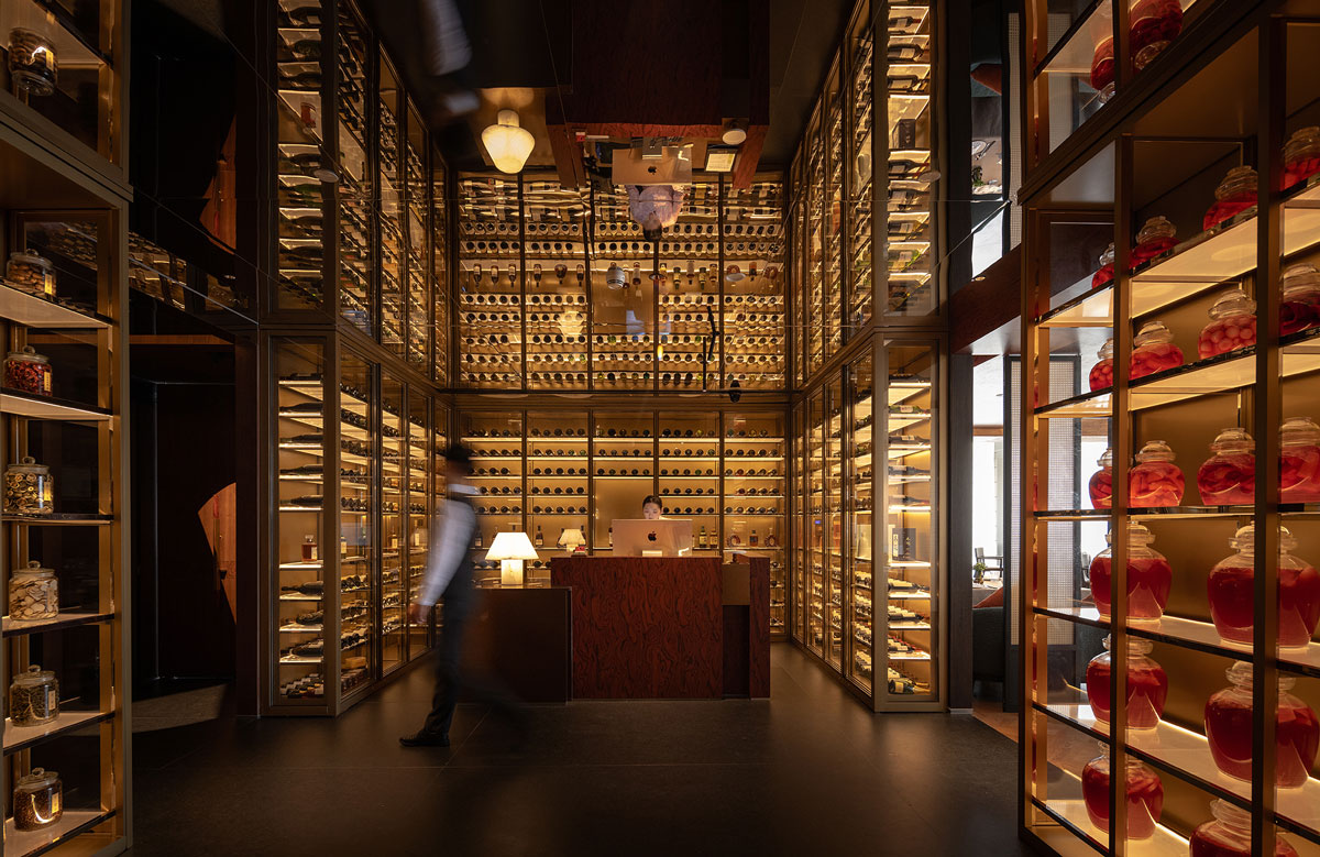 Entrance area of Shu Pavilion Restaurant with full-height wine display, Sichuan ingredients and custom wooden furnishings