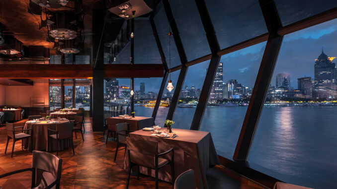 Interni del Shu Pavilion Restaurant a Shanghai con sala da pranzo, grandi vetrate panoramiche e vista sul fiume Huangpu di notte