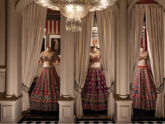 Area espositiva del flagship GG Fort di Gazal Gupta con nicchie scandite da colonne, tende in tessuto e abiti couture illuminati da lampadario decorativo.