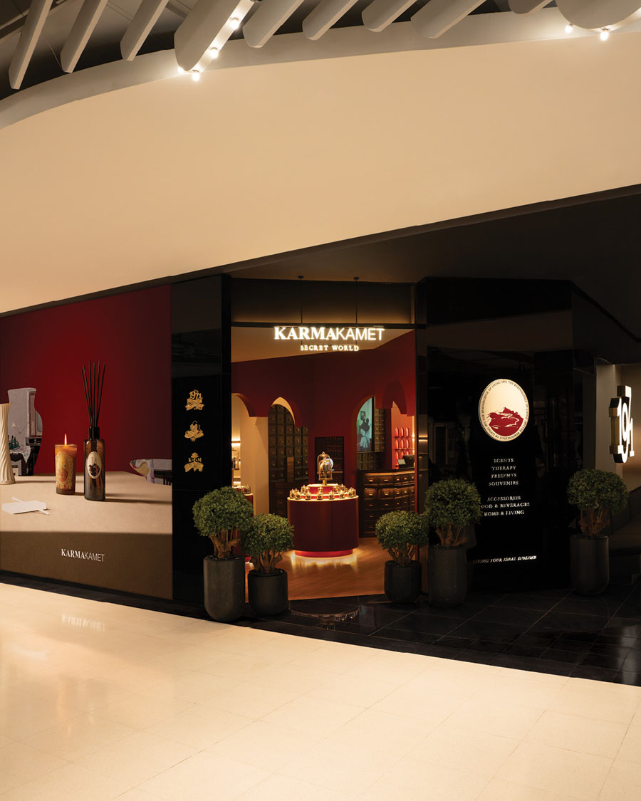 Entrance of the Karmakamet store in Bangkok with a black faรงade, deep red interiors and a central display island