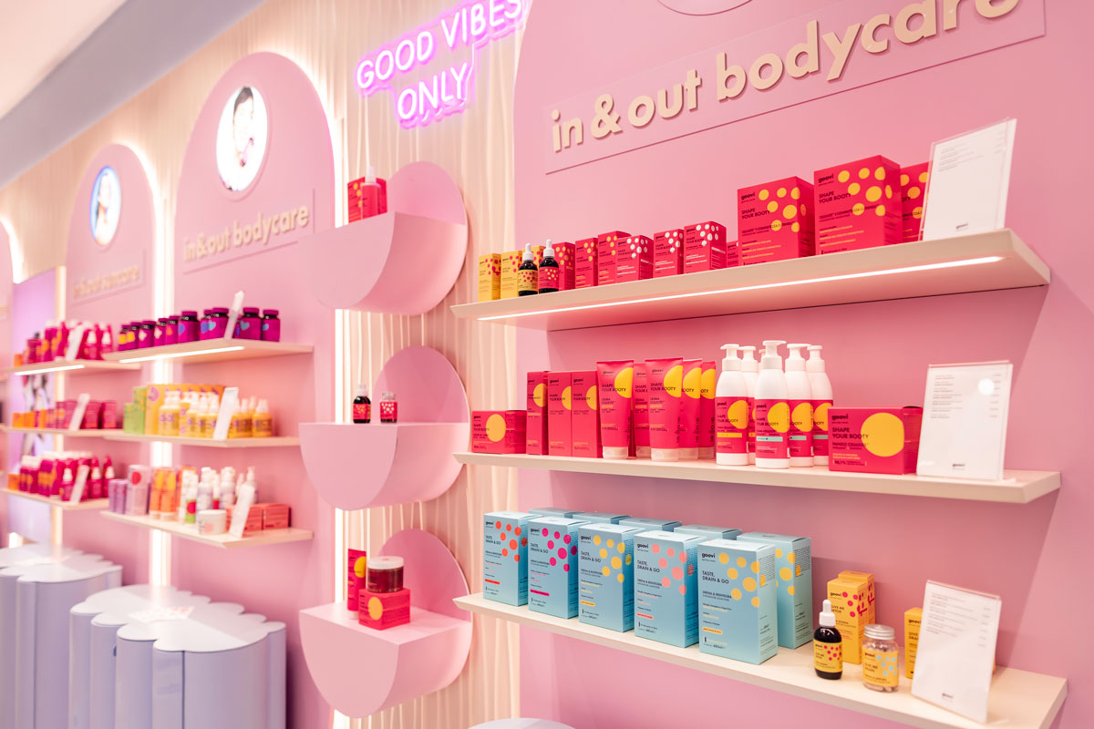 Goovi product displays inside the brand's first flagship store in Grugliasco, featuring illuminated shelving, a pink colour palette and dedicated skincare, bodycare and supplement areas.