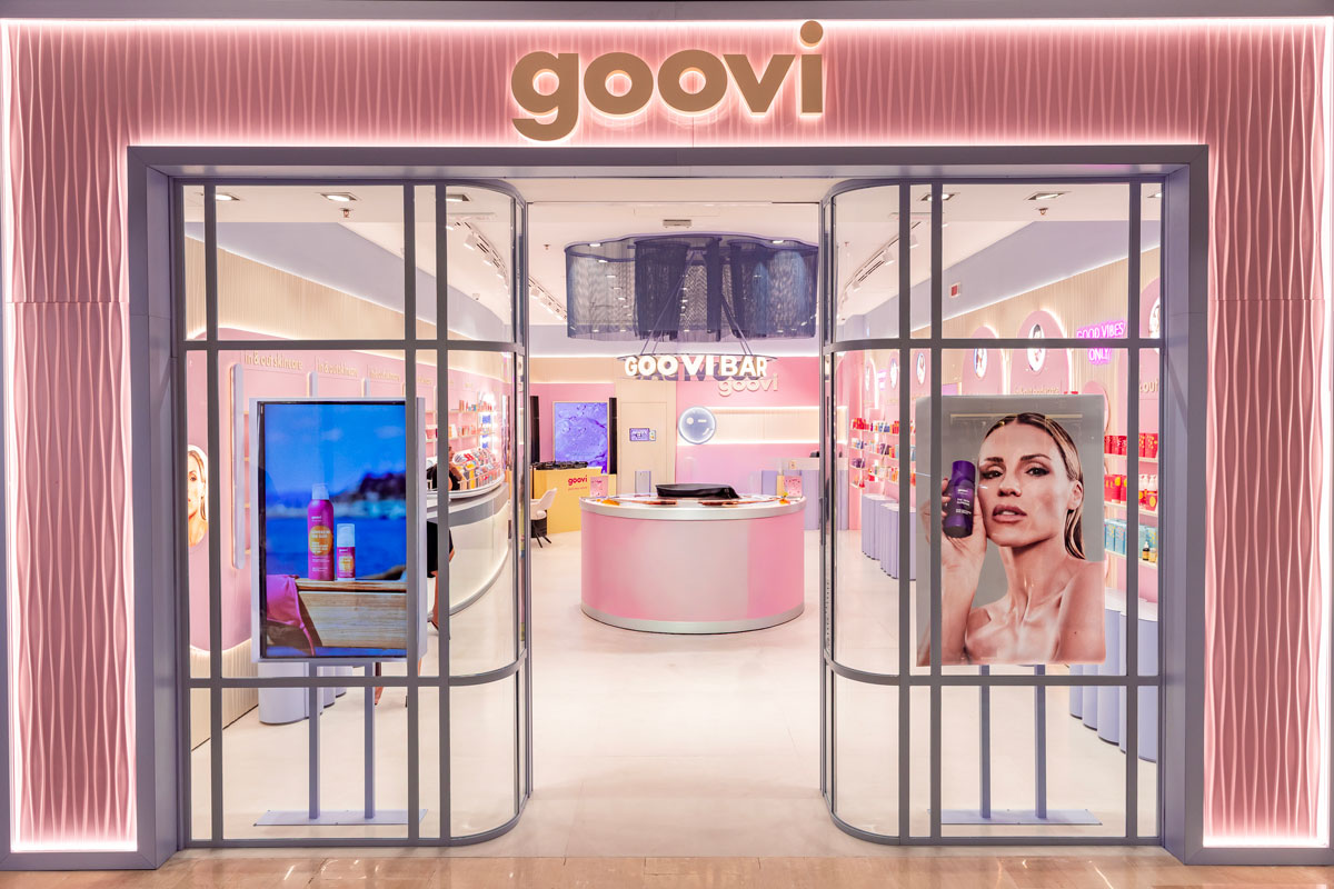 Front façade of Goovi's first flagship store at Le Gru Shopping Centre in Grugliasco, featuring a glazed entrance, illuminated branding and a view of the central Goovi Bar.