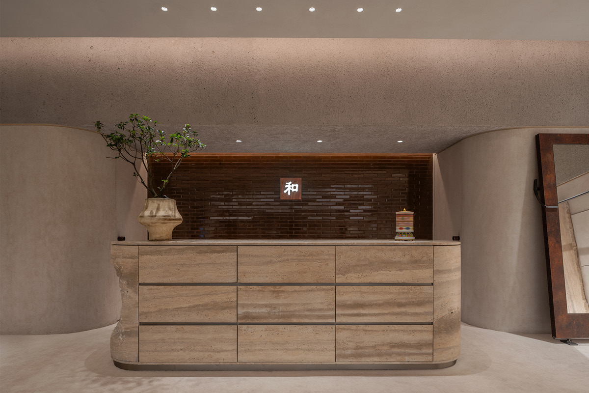 Travertine reception counter in the Hé showroom with a feature wall and integrated lighting