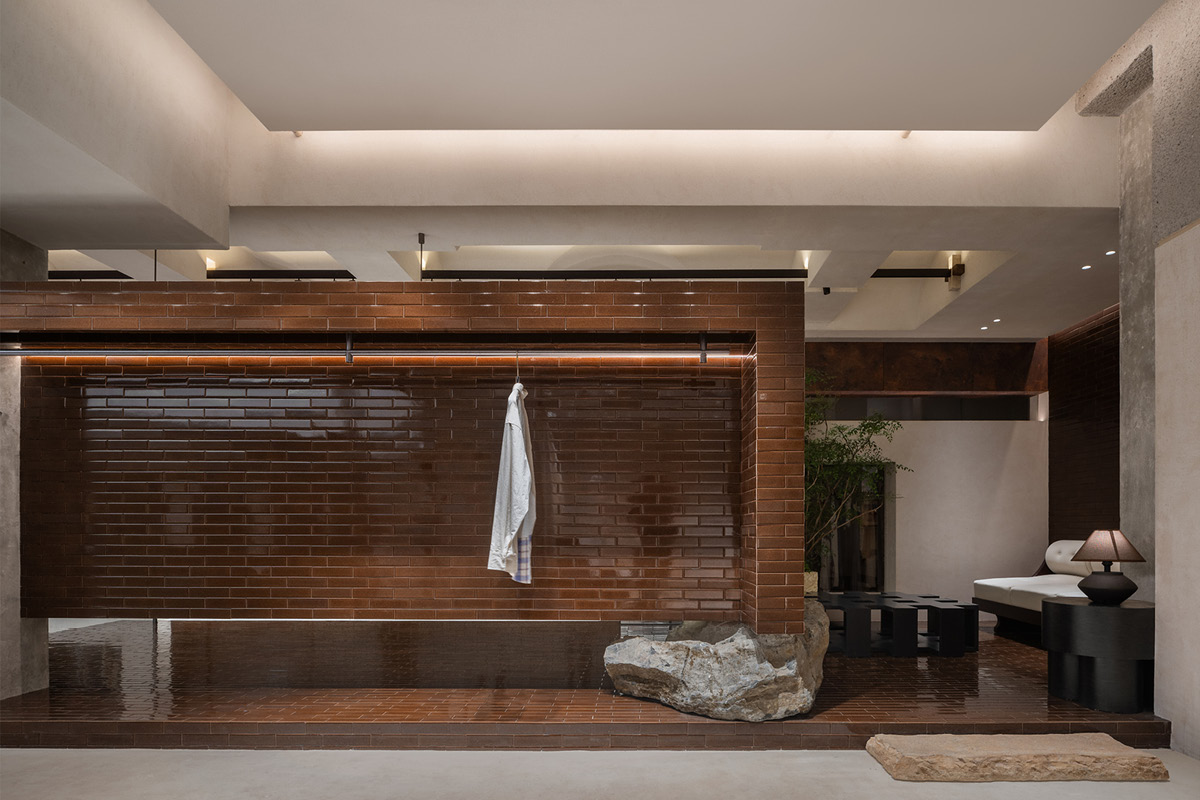 Display system in the Hé showroom with modular wall cladding, integrated linear lighting and natural stone