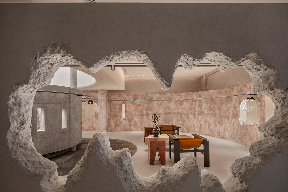 Sculptural opening in the Hé showroom overlooking the lounge area, curved walls and concrete structure