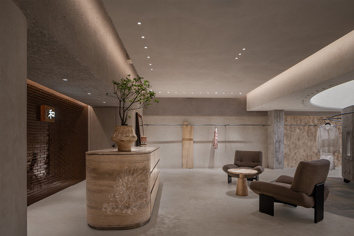 Reception area in the Hé showroom with a travertine counter, waiting area and lighting integrated into the ceiling